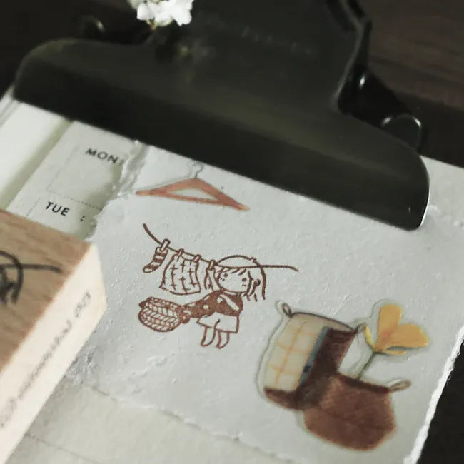 Rubber stamp with a design of a girl and laundry on a white surface.
