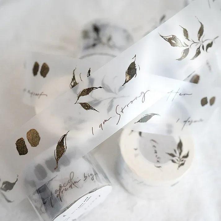 White ribbon-style strip of Leaves PET Tape with gold leaf accents and text on white, detail shot