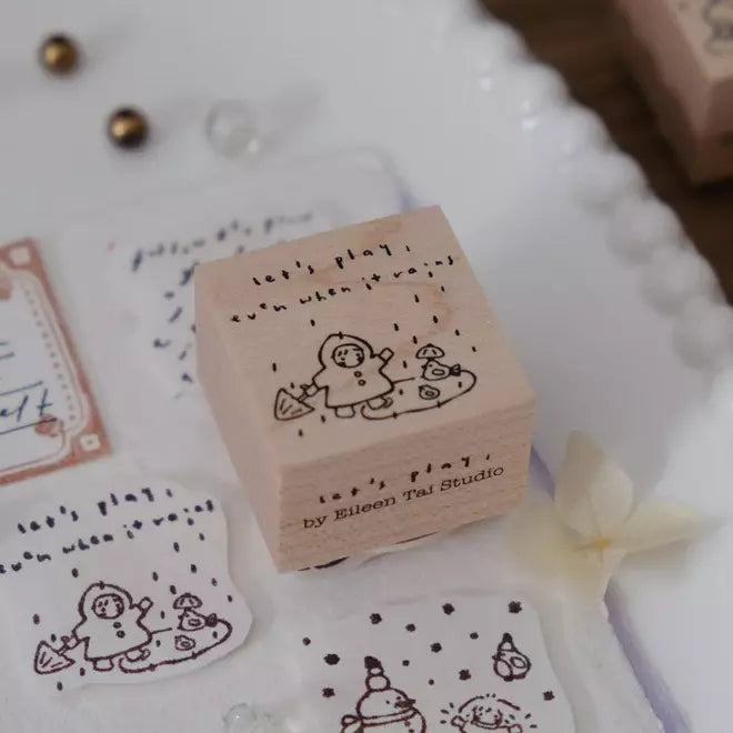 Let's Play Even When It Rains stamp with a snowman design on a decorative surface