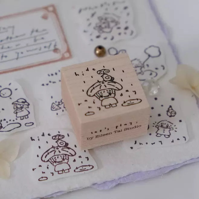 Let's Play Rainy Day stamp with its cartoon weather design on a white fabric background