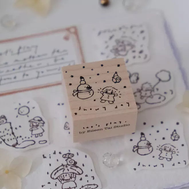 Let's Play Snowy Day stamp with printed illustrations displayed on a white surface