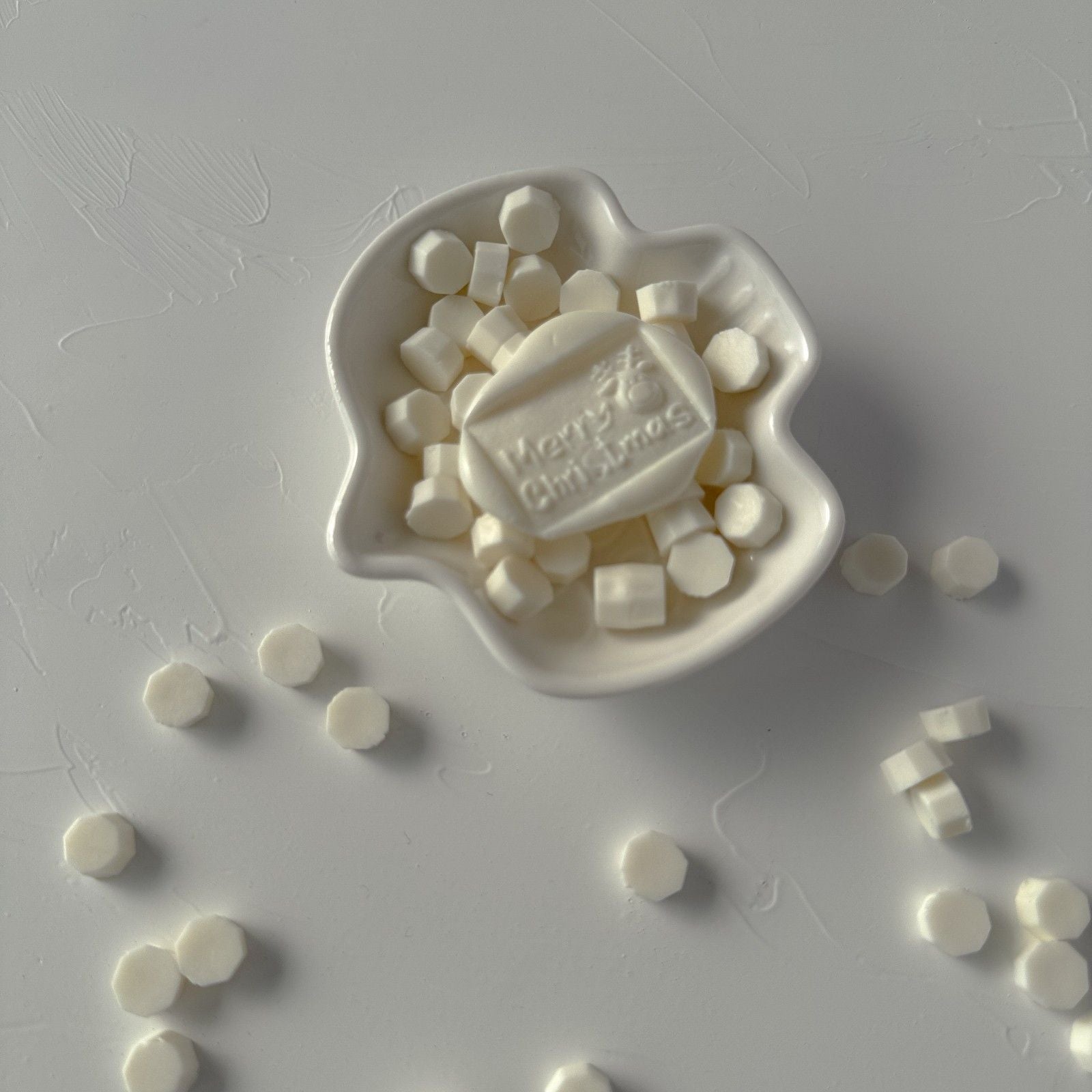 White candy mold with 'Happy Christmas' text on a gray surface with scattered candies.