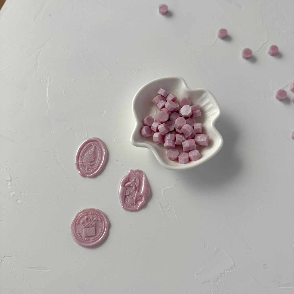 Light Lavender sealing wax beads in a heart-shaped dish with delicate styling props on a light grey surface