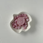 White dish with pink candies and a logo on a light gray background