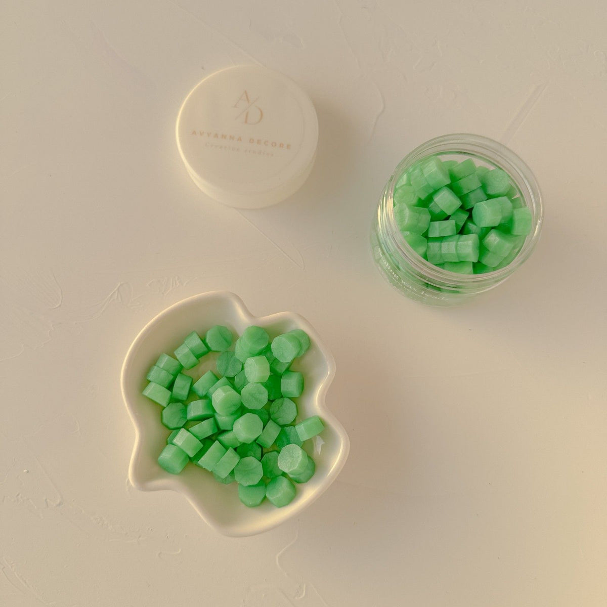 Bright Lime Life Wax Beads in a glass jar and on a plate, zesty green tones on a warm beige background