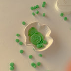 Green candies in a white leaf-shaped dish on a beige surface