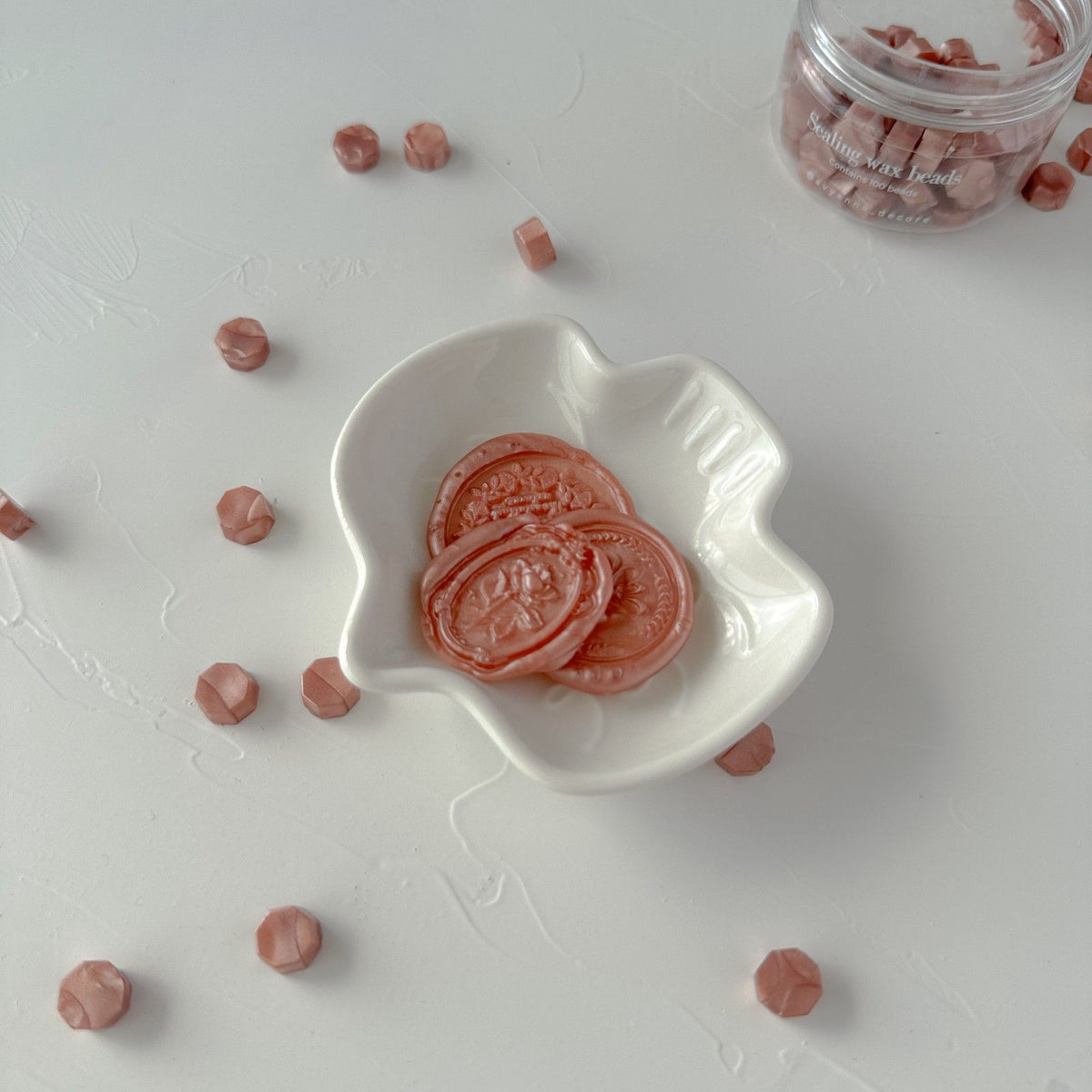 Lingering Brew sealing wax bead slices arranged in a white heart-shaped bowl on a light grey backdrop