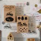 Set of wooden stamps with village and nature designs on a textured surface.