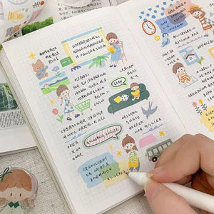 Notebook decorated with Little Thing Washi Tape illustrations with a hand holding a pen