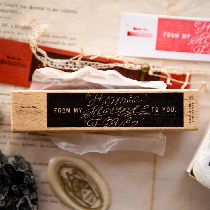 Love Label Rubber Stamp by OURS Studio on a wooden block with engraved text on a textured surface