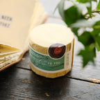 Small bottle wrapped in paper with a green label on a wooden surface