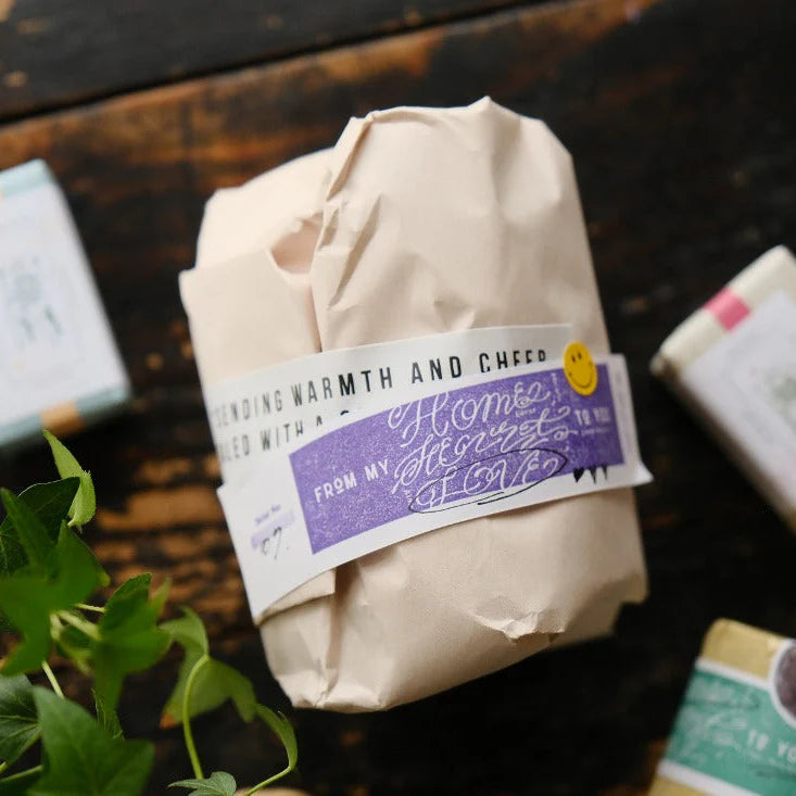 Package sealed with a Love Label Rubber Stamp impression styled with plants on a wooden surface