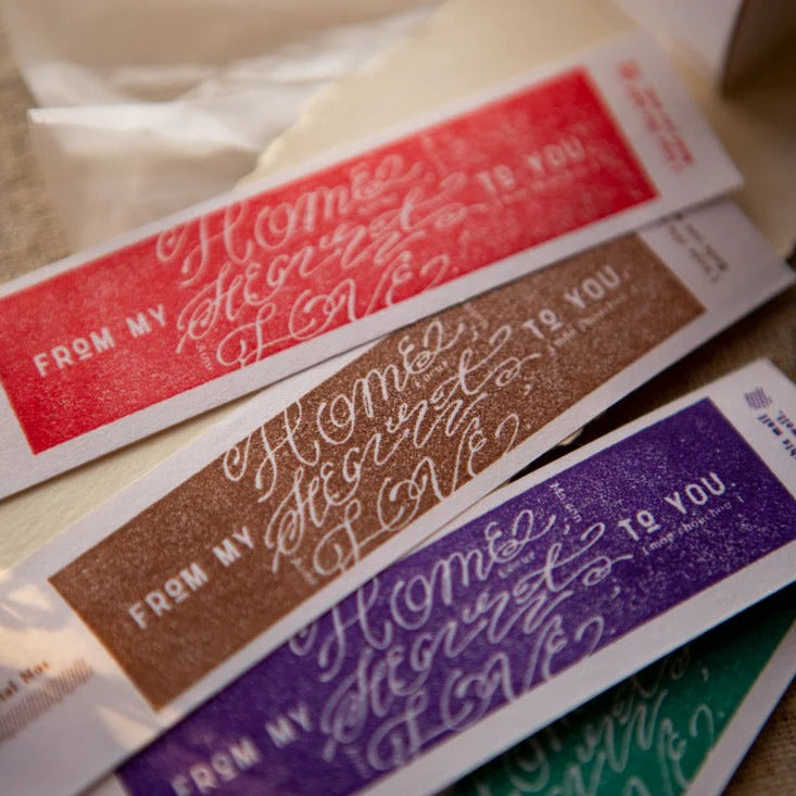 Colorful Home Sweet Home labels stamped with the Love Label Rubber Stamp on a wooden surface