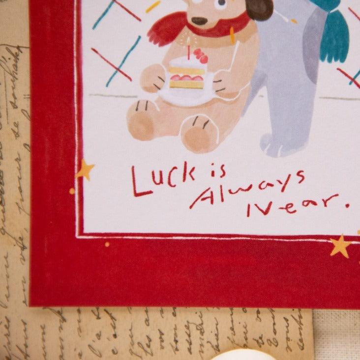 Illustration of a bear holding a cake with text 'Luck is Always IV-year' on a decorative card.