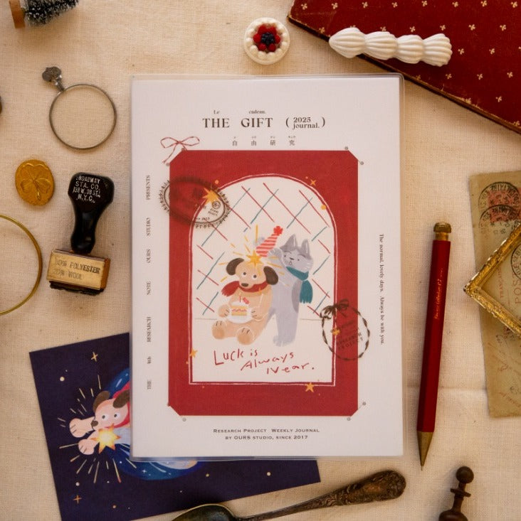 Journal with illustration of two bears and text 'Luck is Always Awaits' on a decorative surface with stationery items.