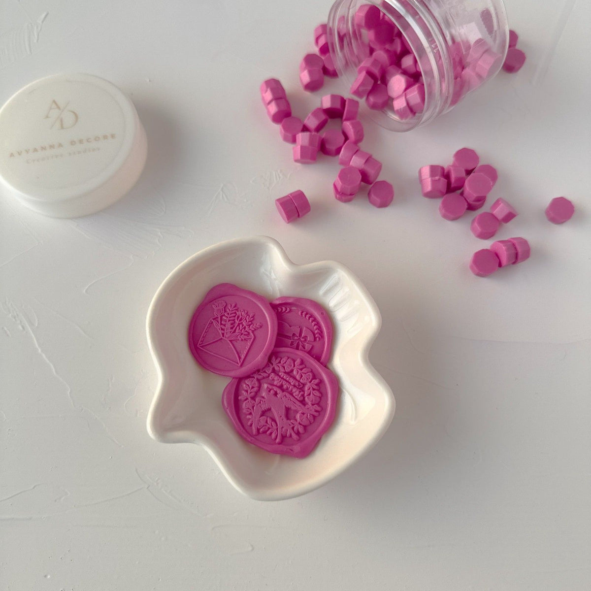 Magenta Pink Wax Beads with stamped seals and stamping tools laid out together on a clean white surface