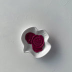 Two purple cookies in a white bowl on a gray surface