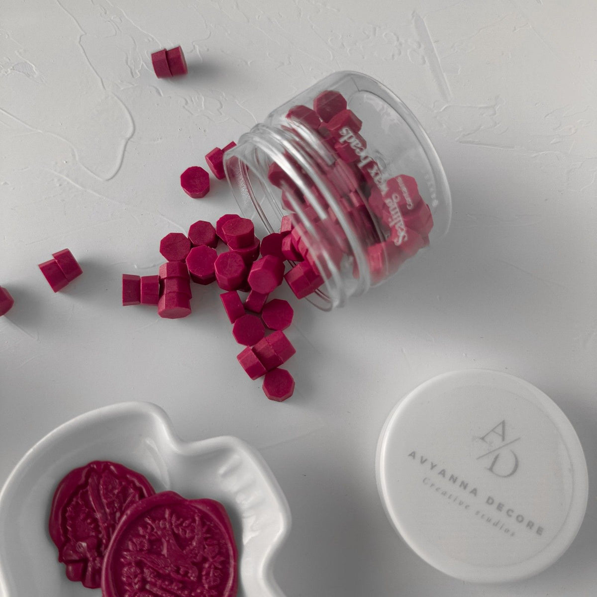 Stamped Magenta Rush wax seals in a clear container on a white surface with Avyanna Decore branding