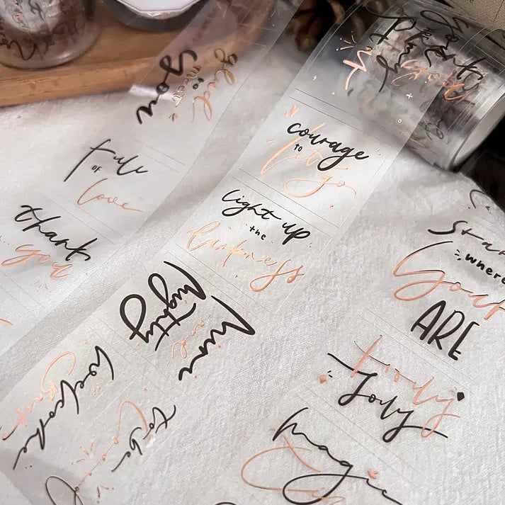 Translucent Magic Time Rose Gold PET Tape sheets with script text arranged on a textured surface