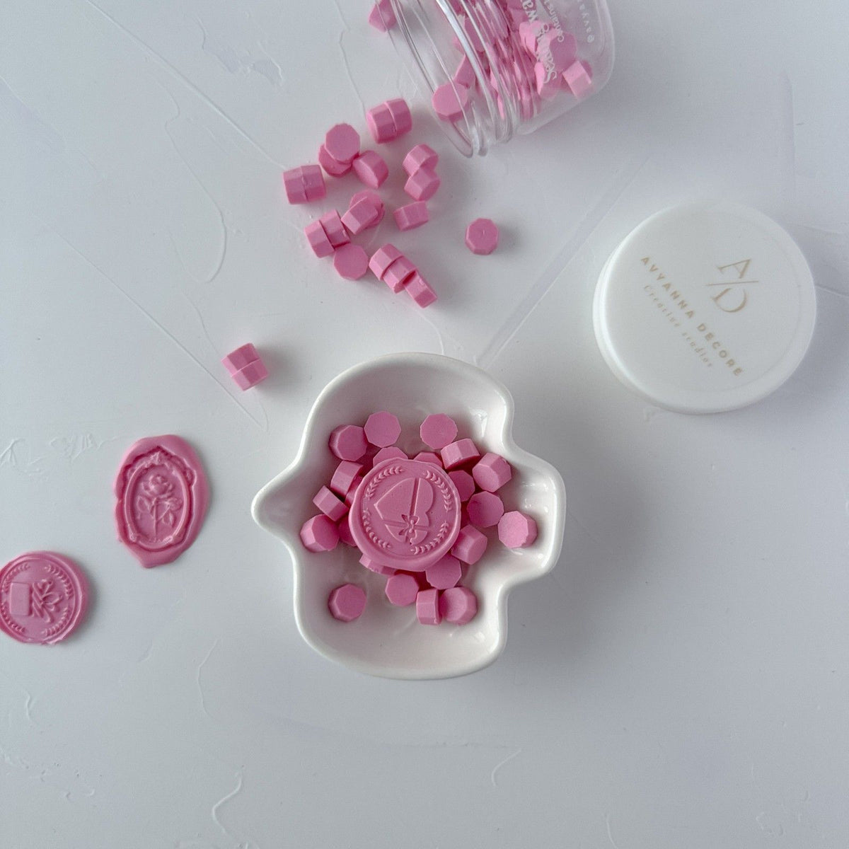 Maiden Pink Wax Beads seals in a white dish with the container of soft pink beads on a grey background