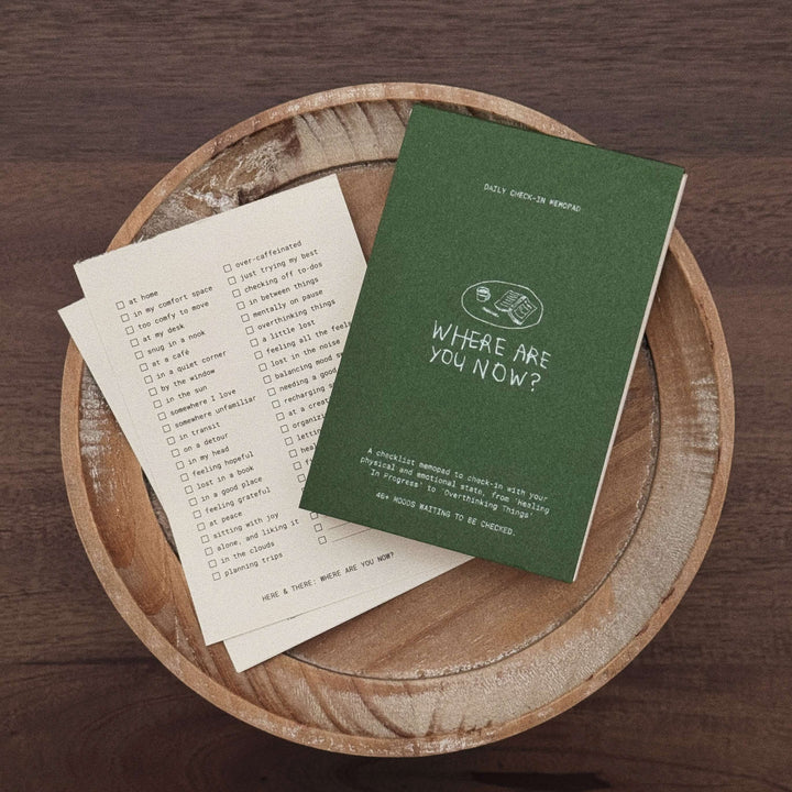 Green notebook and paper on a wooden surface