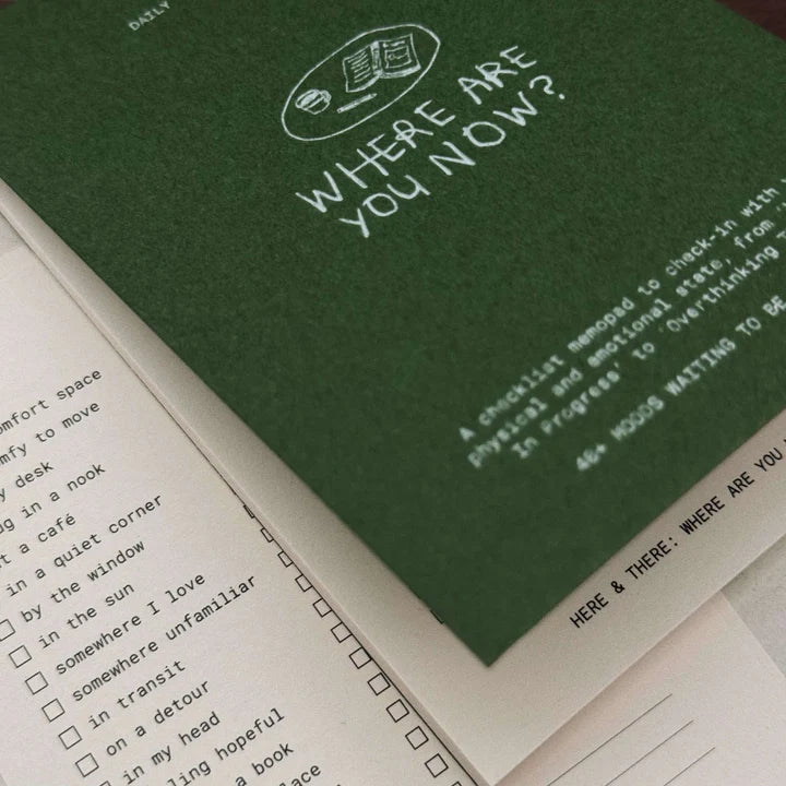 Green notebook with 'Where Are You Now?' text and a checklist on white paper.