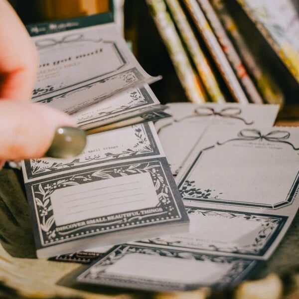 Hand holding a fanned stack of You Got Mail Memo Pad sheets showing the design variety