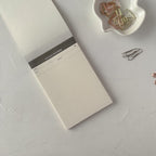 Notebook with a pen holder and paper clips on a light gray surface