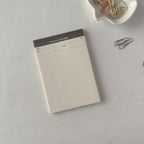 Notepad with a black top section on a light gray surface