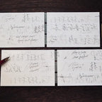 Four white cards with handwritten text on a dark wooden surface