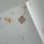 Decorative pendant on a chain over a calendar page