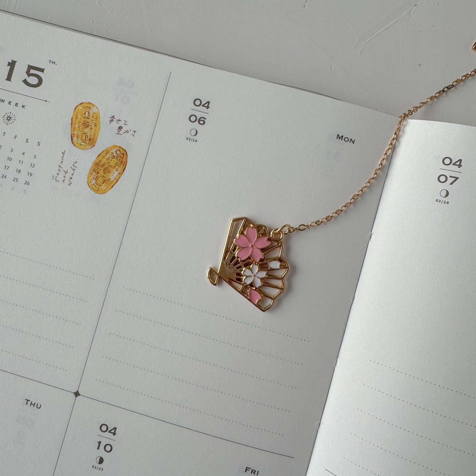 Gold necklace with floral pendant on a calendar page