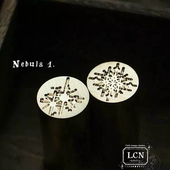 Two round metallic stencils with starburst patterns on a black background, labeled 'Nebula 1'.