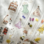 Collage of small figurines, dresses, and nature elements on a textured white surface.