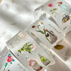 Rolls of decorative tape with floral and bottle designs on a textured surface.