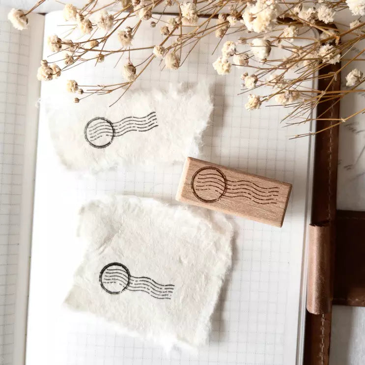 Mini Postal I Rubber Stamp with postal symbol impression on paper surrounded by dried flowers