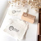 Wooden stamp with a postal stamp design on a white fabric background