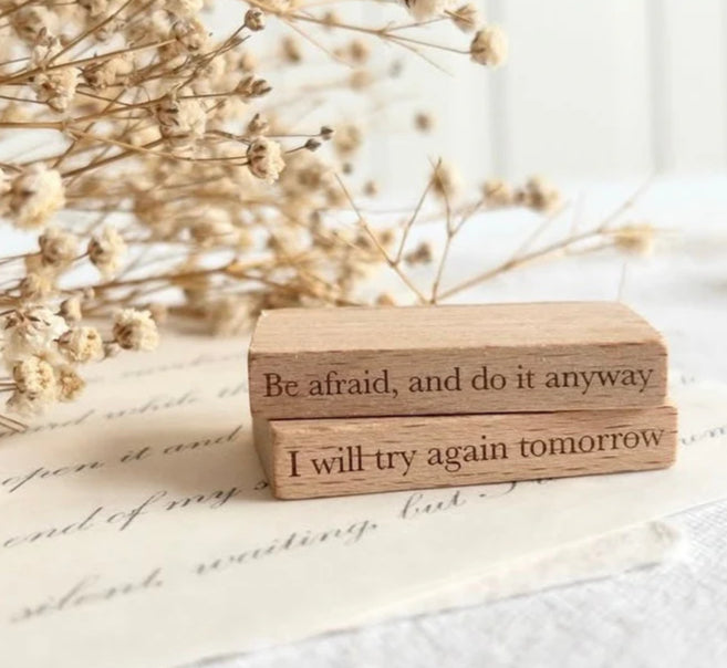 Mini Quote Rubber Stamp set of two wooden blocks with motivational phrases beside dried flowers