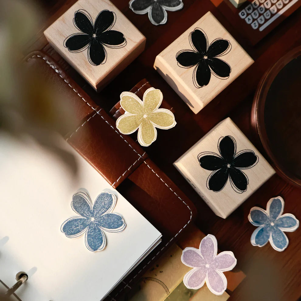 Monochrome Flower Rubber Stamp by Yier flower-shaped stamp on a desk with a notebook and pen