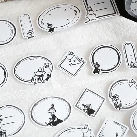 Sheet of black and white Moomin Label Sticker Tape illustrated labels on a light background, top view