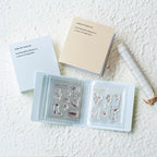 Set of clear stamps in an open book on a textured white surface with notebooks and a ruler.