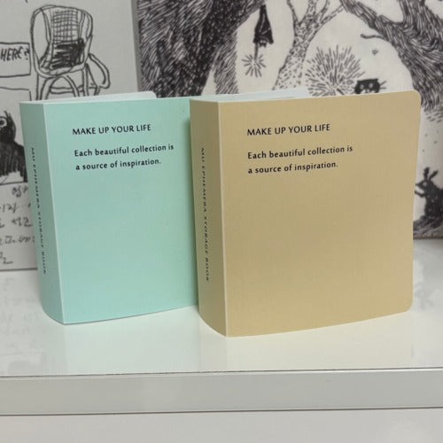 Two MU Ephemera Storage Books with motivational cover text on a patterned white surface