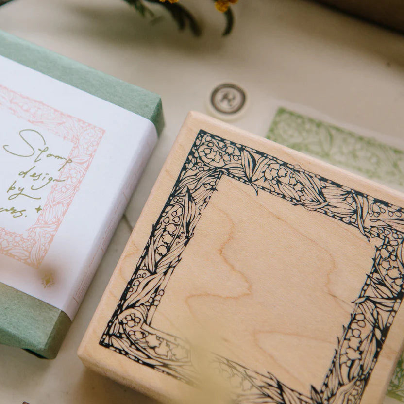 Muguet Frame Rubber Stamp wooden block with lily of the valley design on a white surface