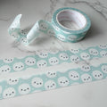 Munchkin Heads Light Teal Washi Tape Roll of decorative tape with cloud designs on a marble surface