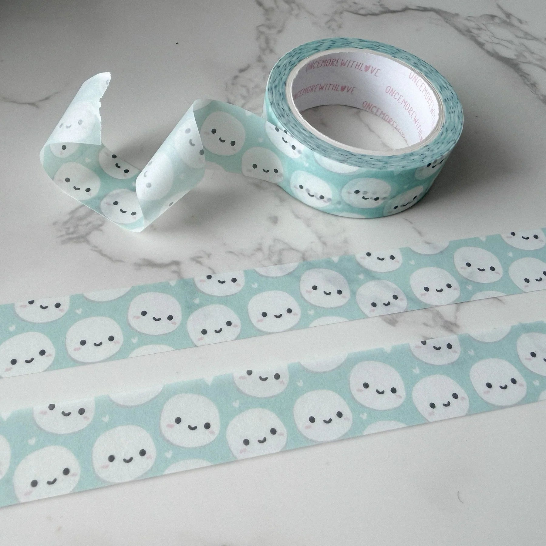 Munchkin Heads Light Teal Washi Tape Roll of decorative tape with cloud designs on a marble surface