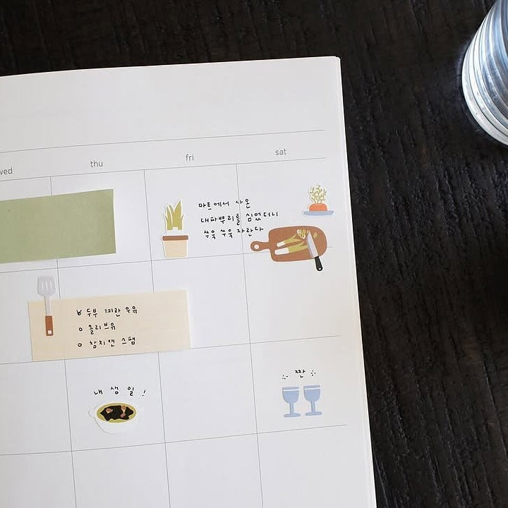 Calendar with illustrated stickers on a wooden surface, from the My Kitchen Sticker Sheet