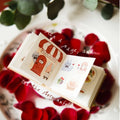 Small open book with illustrations on a bed of red petals