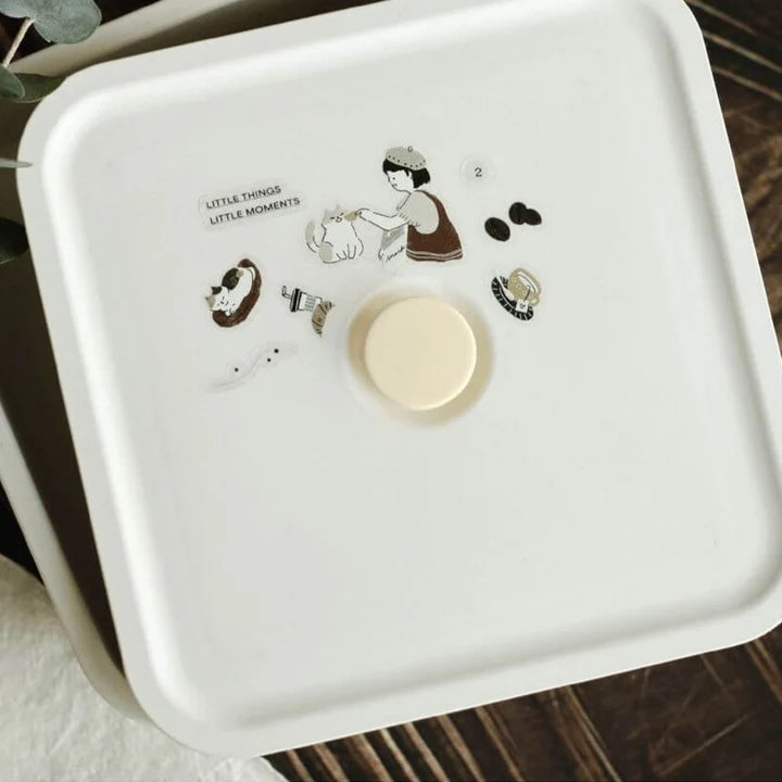 White gift box decorated with Neko Cafe PET Tape illustrations and a gold button on wood