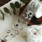 Decorative tape with cartoon designs on a surface with green leaves and a glass.