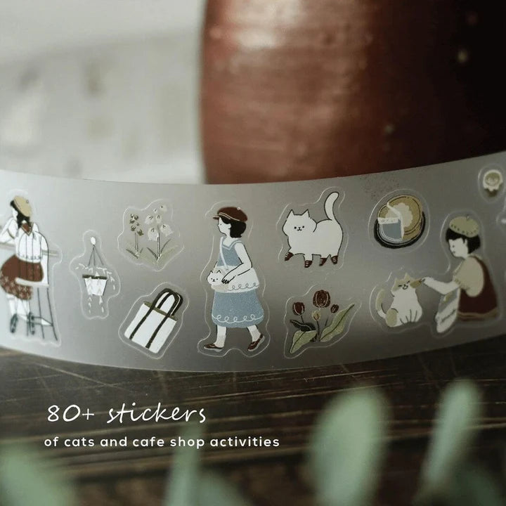 Roll of Neko Cafe PET Tape showing cats enjoying cafe activities, unrolled on a wooden surface